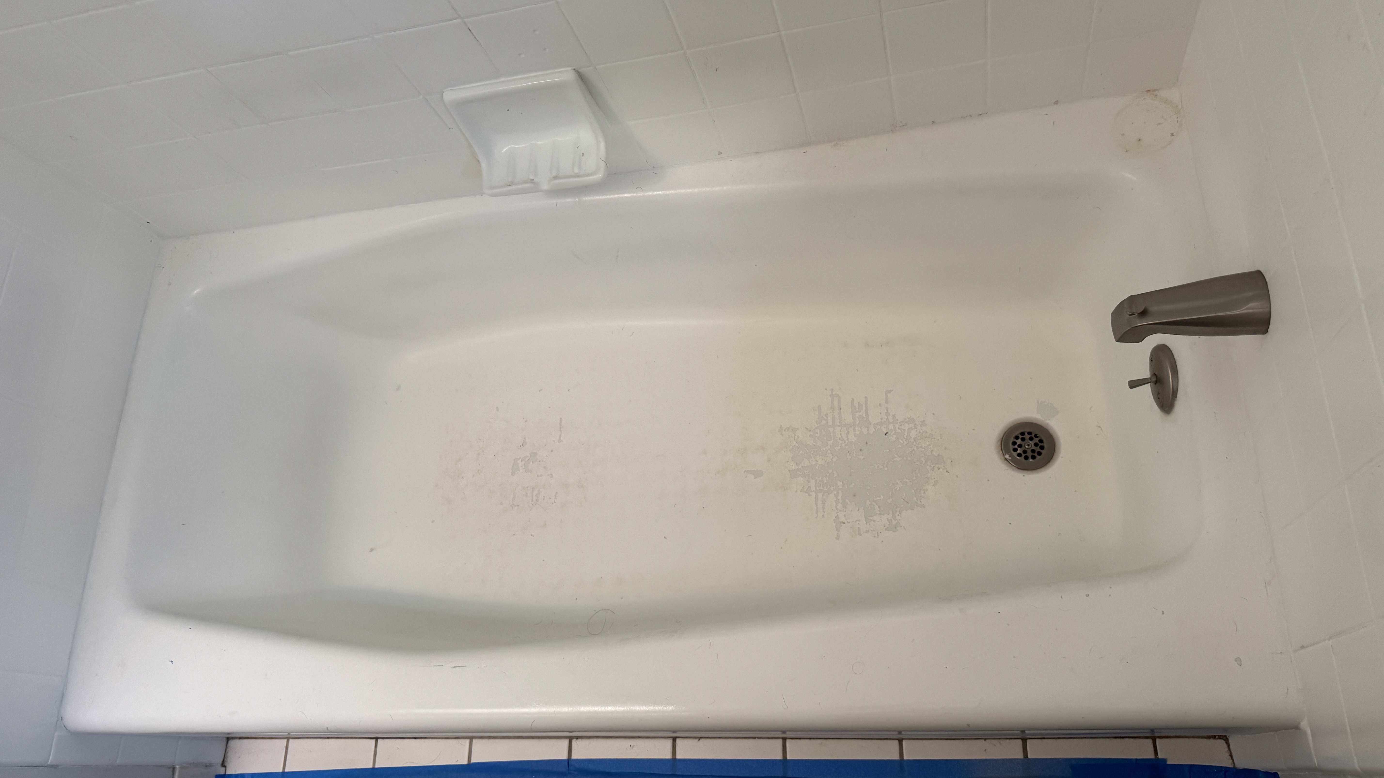 Before reglazing in Oakland, CA &mdash; alcove tub with worn, stained finish and peeling surface
