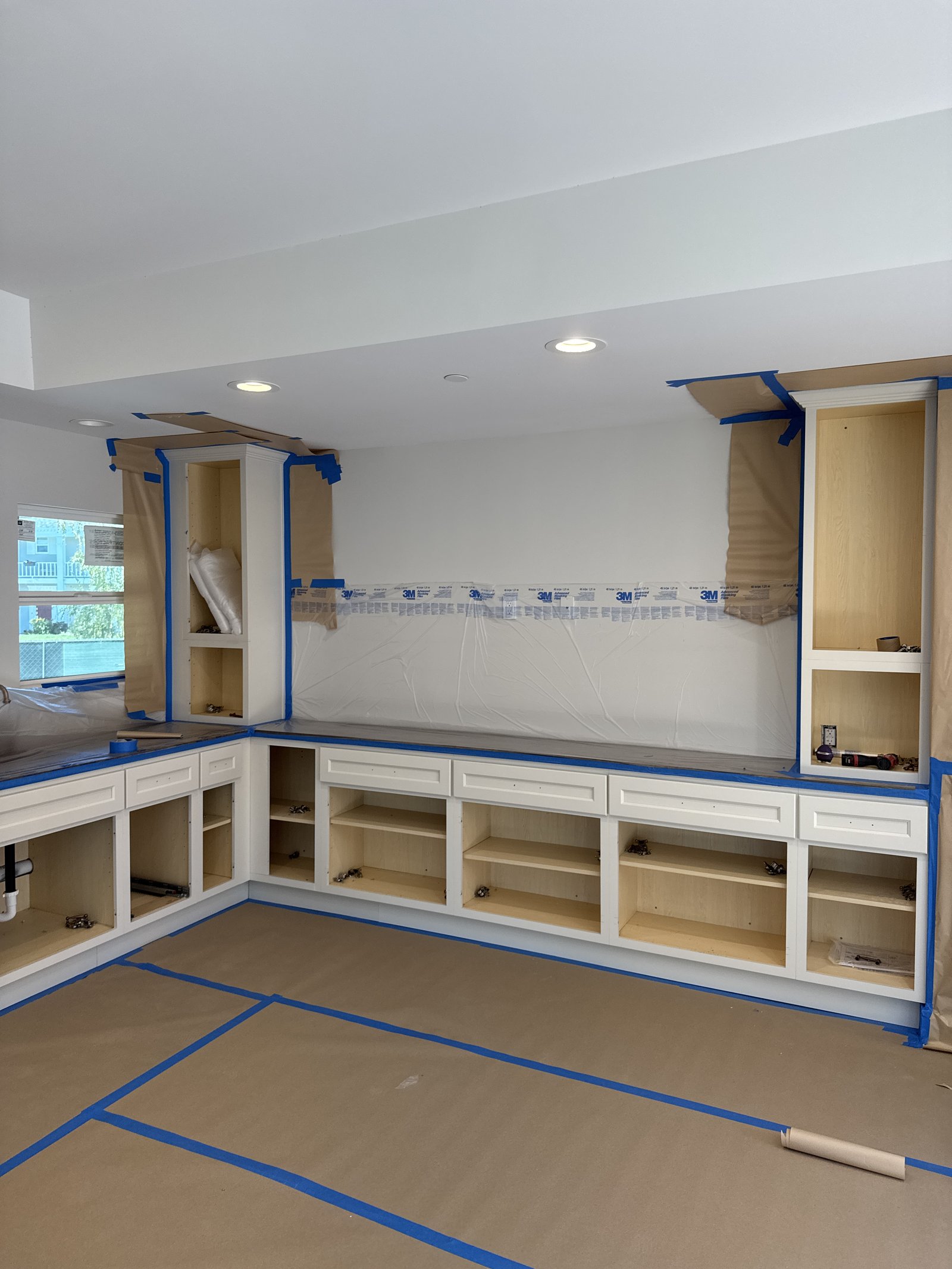 Kitchen cabinet installation &mdash; Base boxes and floor protection staged during build-out &mdash; Santa Clara, CA